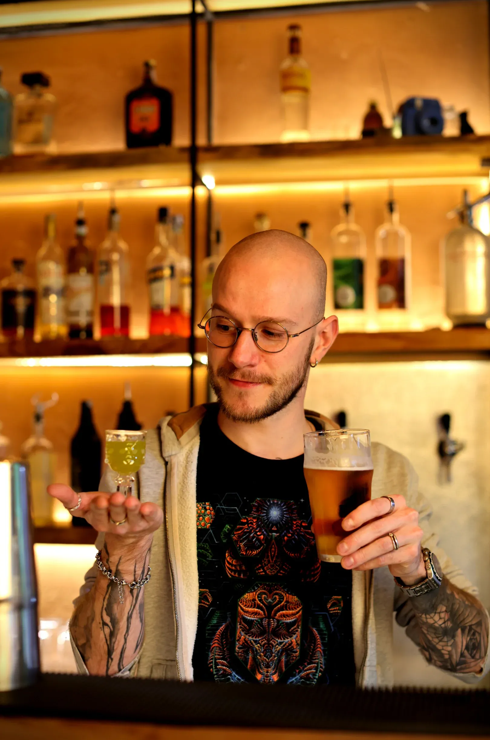 The bartender weighing up a green shot against a pint of beer at the bar counter